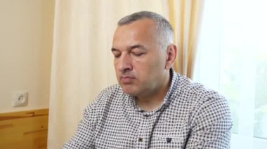 Bir adam masada otururken kaşıkla dondurma yiyor..