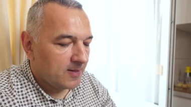 Bir adam masada otururken kaşıkla dondurma yiyor..