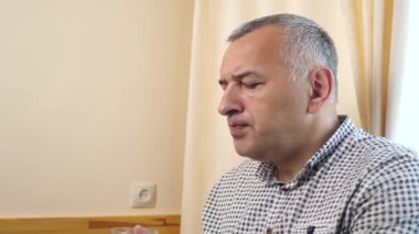 Bir adam masada oturuyor, kurabiye yiyor ve kahve içiyor..