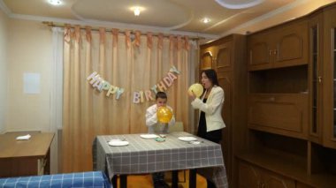 Bir kız ve erkek kardeşi, bir doğum günü partisi için süsleme ve balonlarla bir oda dekore ediyorlar..