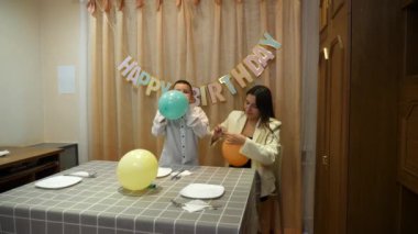 Bir kız ve erkek kardeşi, bir doğum günü partisi için süsleme ve balonlarla bir oda dekore ediyorlar..