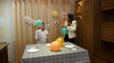 Bir kız ve erkek kardeşi, bir doğum günü partisi için süsleme ve balonlarla bir oda dekore ediyorlar..