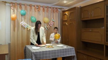 Bir anne, kızı ve oğluyla birlikte doğum günü kutlaması için şenlik masasına servis yapıyor..