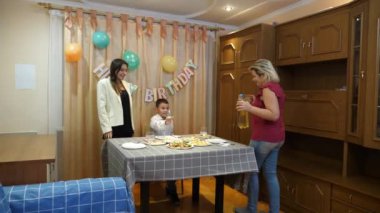 Bir anne, kızı ve oğluyla birlikte doğum günü kutlaması için şenlik masasına servis yapıyor..
