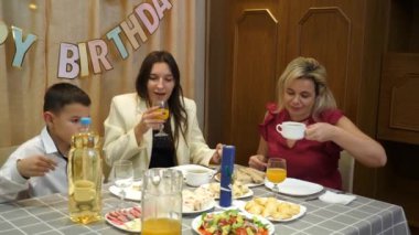 Bir çocuğun doğum gününü kutlarken, insanlar masaya oturur, içki içer ve kendilerini ödüllendirirler. Doğum günü kutlaması.