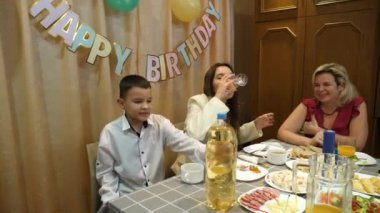Bir çocuğun doğum gününü kutlarken, insanlar masaya oturur, içki içer ve kendilerini ödüllendirirler. Doğum günü kutlaması.