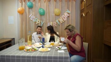 Bir çocuğun doğum gününü kutlarken, insanlar masaya oturur, içki içer ve kendilerini ödüllendirirler. Doğum günü kutlaması.