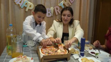 Bir çocuğun doğum gününü kutlarken, insanlar masaya oturur, içki içer ve kendilerini ödüllendirirler. Doğum günü kutlaması.