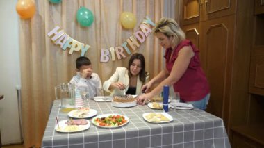 İnsanlar doğum günü pastası yiyor. Pasta, festival masasının önemli bir tatlısıdır..