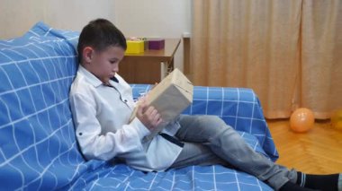 Bir çocuk doğum gününde ona verilen hediyeleri açar..