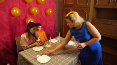 Bir kız ve küçük kardeşi doğum günü kutlaması için bir oda ve şenlik masası dekore ediyorlar..