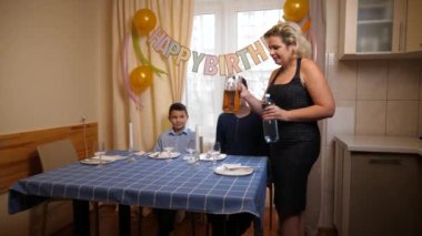 Bir anne, oğlu ve yeğeniyle birlikte doğum gününde şenlik masasına servis yapar. Doğum günü kutlaması.