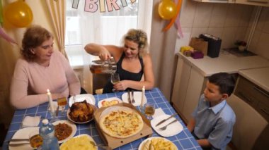 Bir kadının doğum gününü kutlayan insanlar masaya oturur, içer ve kendilerini ödüllendirirler. Doğum günü kutlaması.