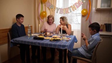 Bir kadının doğum gününü kutlayan insanlar masaya oturur, içer ve kendilerini ödüllendirirler. Doğum günü kutlaması.
