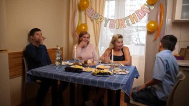 Bir kadının doğum gününü kutlayan insanlar masaya oturur, içer ve kendilerini ödüllendirirler. Doğum günü kutlaması.