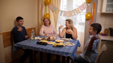 Bir kadının doğum gününü kutlayan insanlar masaya oturur, içer ve kendilerini ödüllendirirler. Doğum günü kutlaması.