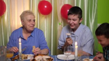 Büyükannenin doğum gününü kutlayan konuklar masaya oturur, içer ve kendilerini ödüllendirirler. Doğum günü kutlaması.