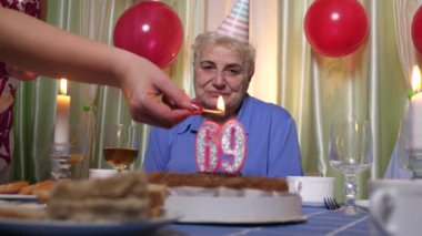 69 yıllık mumlu bir doğum günü pastası masaya servis edilir. Doğum günü kutlaması.