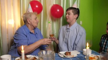 Büyükannenin doğum gününü kutlayan konuklar masaya oturur, içer ve kendilerini ödüllendirirler. Doğum günü kutlaması.