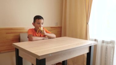 Bir çocuk masada otururken bir muz yer..