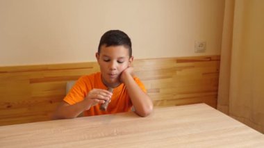 Çocuk masada otururken çikolata yiyor..