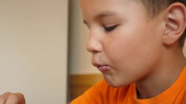 Çocuk masada otururken çikolata yiyor..