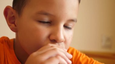 Çocuk masada otururken çikolata yiyor..