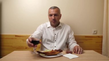 Bir adam akşam yemeği sırasında kırmızı şarap içer. Alkol tüketimi kültürü.