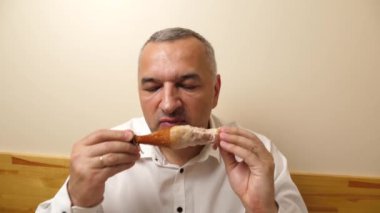 Bir adam masada otururken soslu tavuk yer..