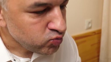 Bir adam masada otururken çatalla salatalık yiyor..