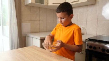 Bir çocuk mutfaktaki bir kaseden patates cipsi yiyor..