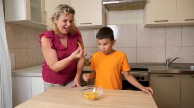 Bir çocuk ve annesi mutfakta patates cipsi yiyorlar..