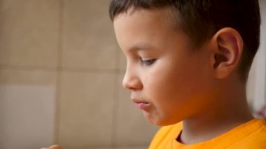 Bir çocuk mutfaktaki bir kaseden patates cipsi yiyor..