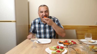 Bir adam masada otururken kırmızı havyarla kanepe yiyor..