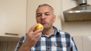 Bir adam mutfakta otururken bir elma yiyor..