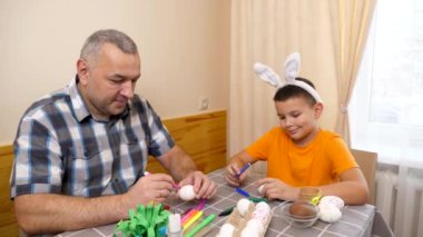 Baba ve oğul Paskalyayı kutluyor. Bir sepet hazırlıyorlar, yumurta boyuyorlar ve eğleniyorlar..