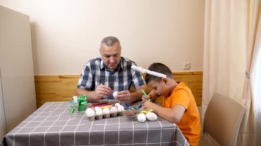 Baba ve oğul Paskalyayı kutluyor. Bir sepet hazırlıyorlar, yumurta boyuyorlar ve eğleniyorlar..