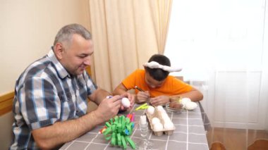 Baba ve oğul Paskalyayı kutluyor. Bir sepet hazırlıyorlar, yumurta boyuyorlar ve eğleniyorlar..