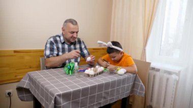 Baba ve oğul Paskalyayı kutluyor. Bir sepet hazırlıyorlar, yumurta boyuyorlar ve eğleniyorlar..