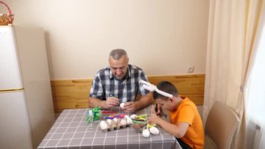 Baba ve oğul Paskalyayı kutluyor. Bir sepet hazırlıyorlar, yumurta boyuyorlar ve eğleniyorlar..
