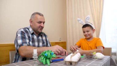 Baba ve oğul Paskalyayı kutluyor. Bir sepet hazırlıyorlar, yumurta boyuyorlar ve eğleniyorlar..