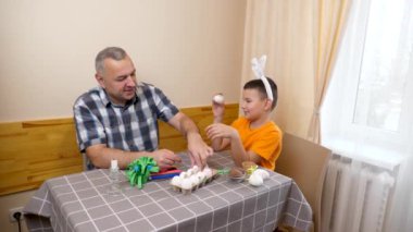 Baba ve oğul Paskalyayı kutluyor. Bir sepet hazırlıyorlar, yumurta boyuyorlar ve eğleniyorlar..