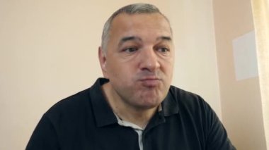 Bir adam masada otururken hamburger yiyor..