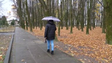 Yağmurlu havada parkta yürüyen bir kadın..