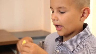 Çocuk masada otururken peynir yiyor..