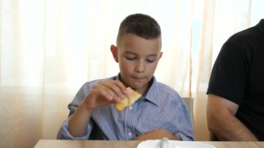 Baba ve oğul masada yemek yer, yemek yer ve içki içerler..