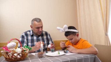 Baba ve oğul Paskalyayı kutluyor. Bir sepet hazırlıyorlar, yumurta boyuyorlar ve eğleniyorlar..