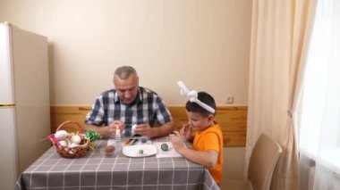Baba ve oğul Paskalyayı kutluyor. Bir sepet hazırlıyorlar, yumurta boyuyorlar ve eğleniyorlar..