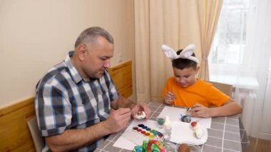 Baba ve oğul Paskalyayı kutluyor. Bir sepet hazırlıyorlar, yumurta boyuyorlar ve eğleniyorlar..
