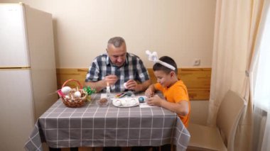 Baba ve oğul Paskalyayı kutluyor. Bir sepet hazırlıyorlar, yumurta boyuyorlar ve eğleniyorlar..